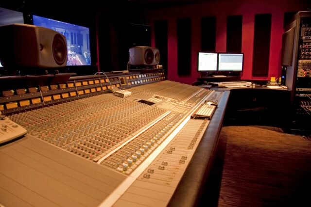 Mixing console in recording studio with black acoustic panels on rear wall