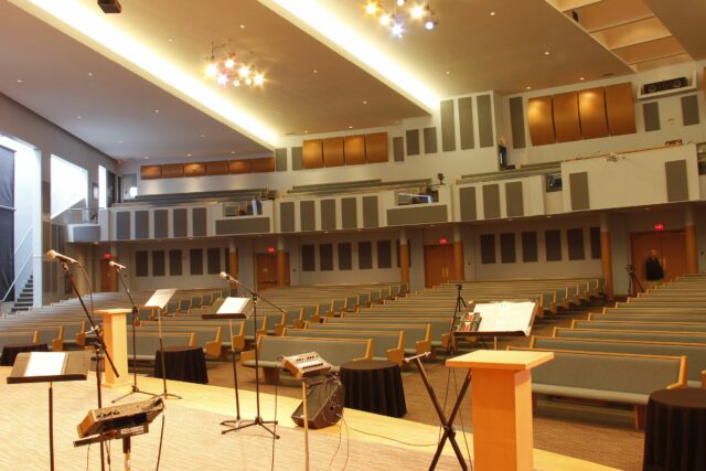 View from behind pulpit of empty church with grey acoustic panels on back wall