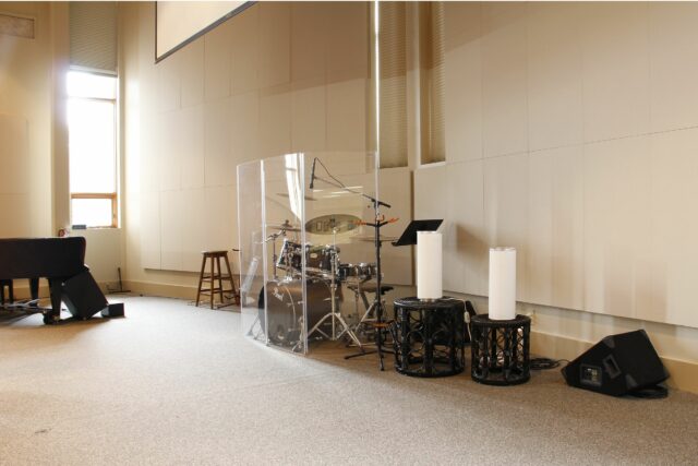 Drum set on church stage with light grey acoustic panels on wall behind
