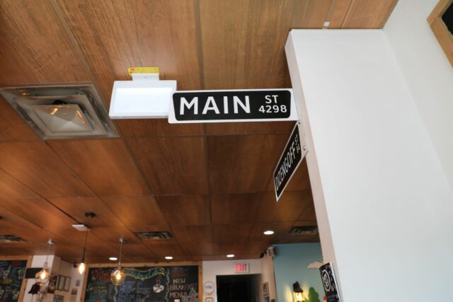 Street sign attached to brown T-bar ceiling made with acoustic panels