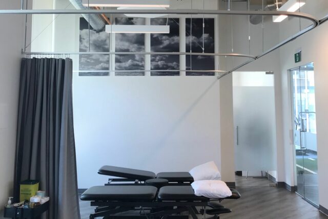 Two black physio beds in open white room with four custom printed acoustic panels on the wall.