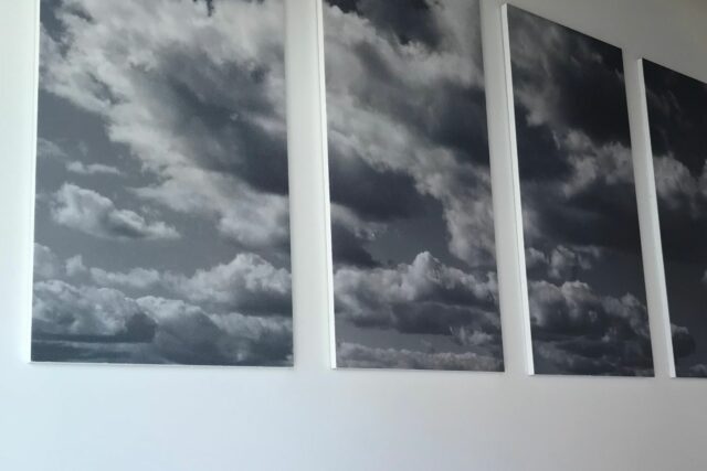 Acoustic panels with cloud design print hanging on a white wall.