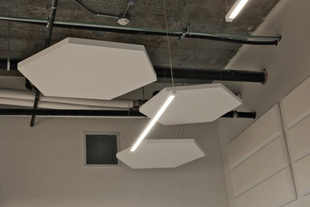 White hexagon acoustic ceiling panels suspended from ceiling