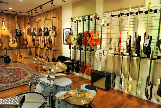 Guitars hanging on wall in showroom with beige acoustic panels on walls.