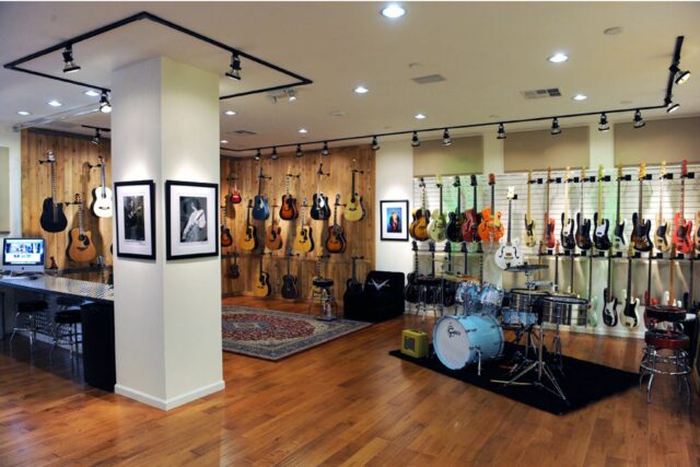 Guitar showroom with beige acoustic panels on wall.