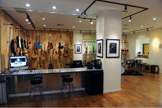 Metal bar in guitar showroom with beige acoustic panels on back wall.