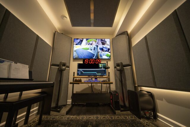 Studio control desk with monitor above and grey acoustic panels and bass traps on walls and ceiling