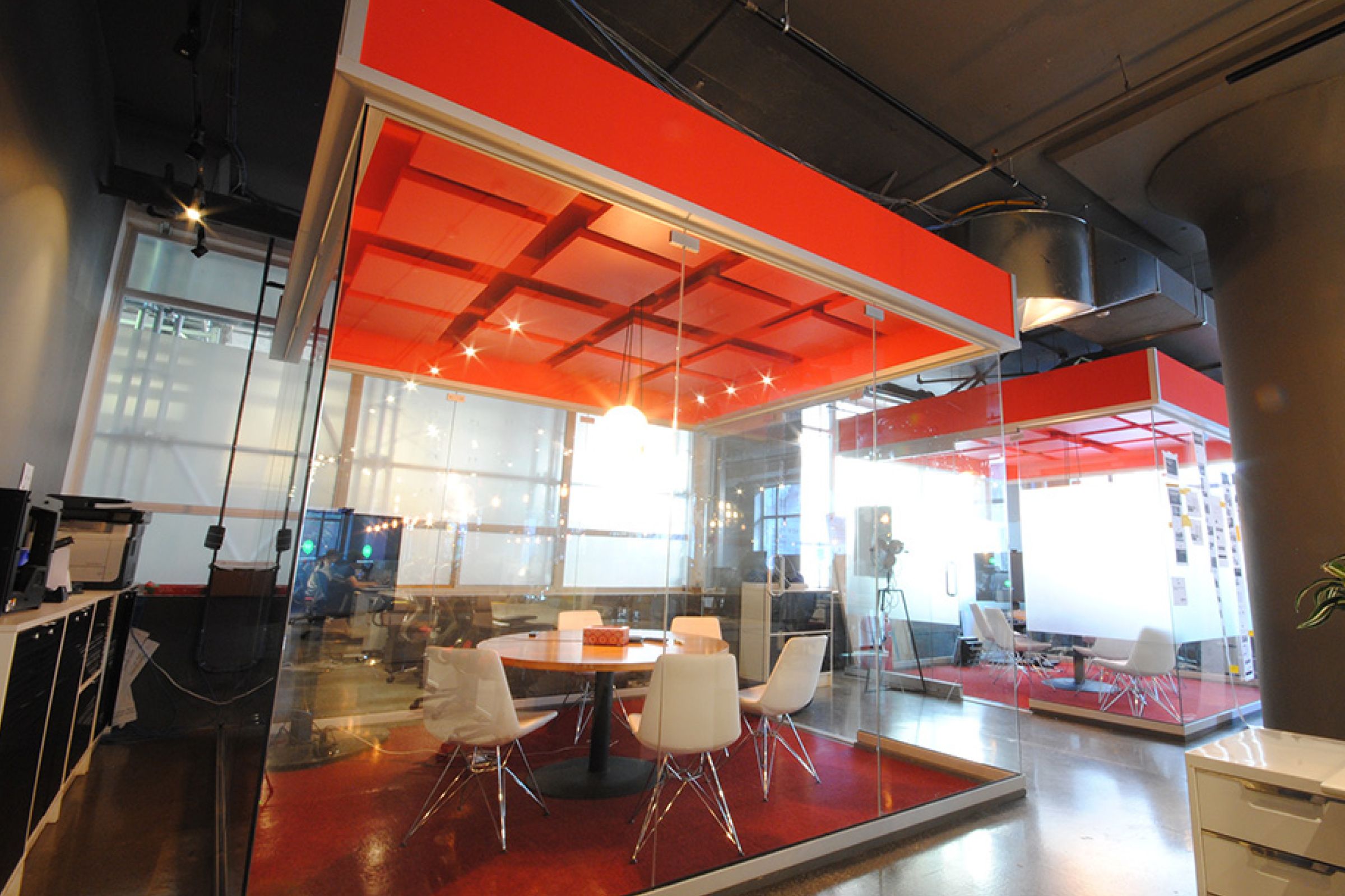 Meeting room with glass walls and red acoustic panels on a red ceiling