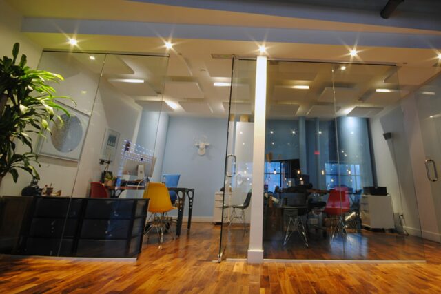 Two office rooms with glass doors and white acoustic ceiling panels