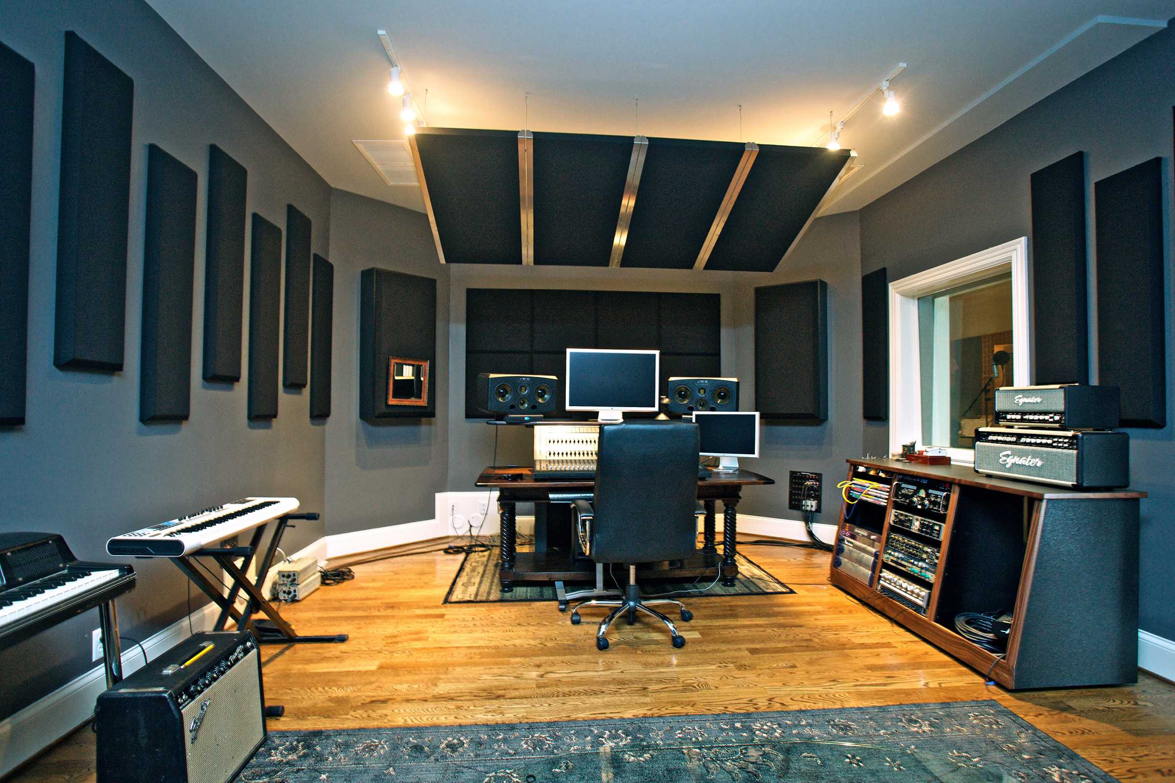 Recording studio mixing station with grey acoustic panels on ceiling above desk and on surrounding walls