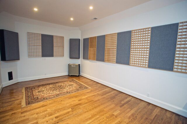Empty recording studio room with grey acoustic panels and wooden acoustic diffusers on white walls