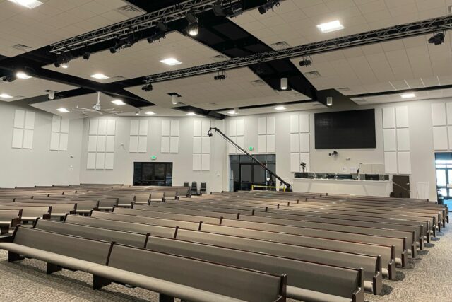 View of church pews with white acoustic panels installed on the back wall