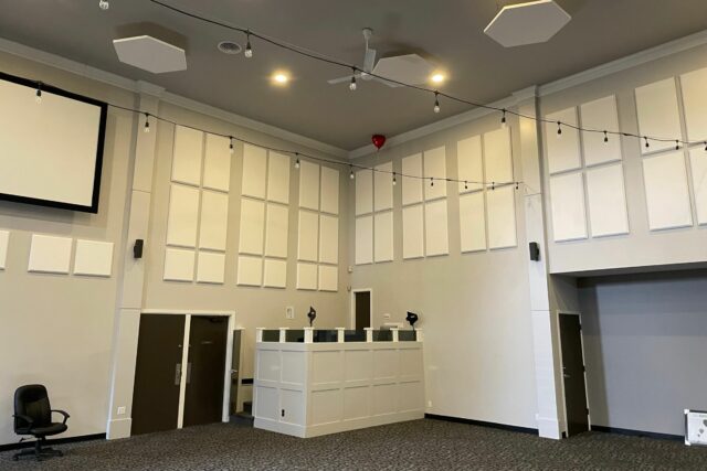 Church with white walls and numerous white acoustic wall panels and ceiling clouds