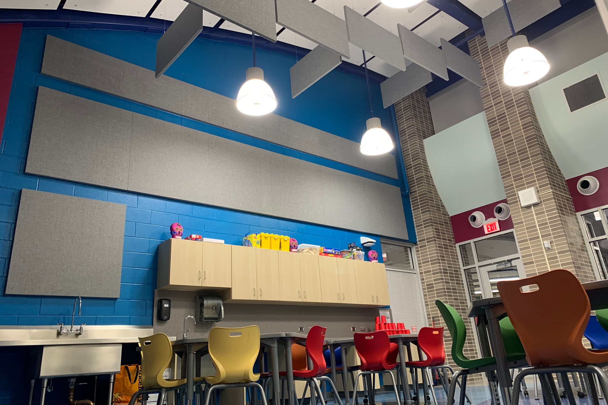 Grey acoustic wall panels and hanging acoustic baffles installed in a daycare centre