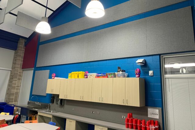 Daycare space with grey acoustic panels installed on a blue wall