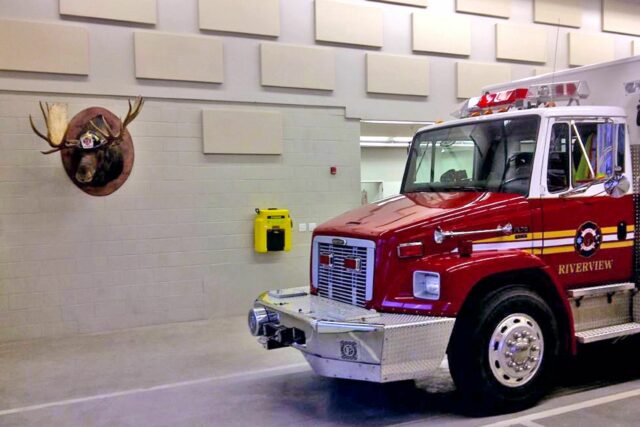 Firetruck in fire station parking garage with white acoustic panels installed on the wall