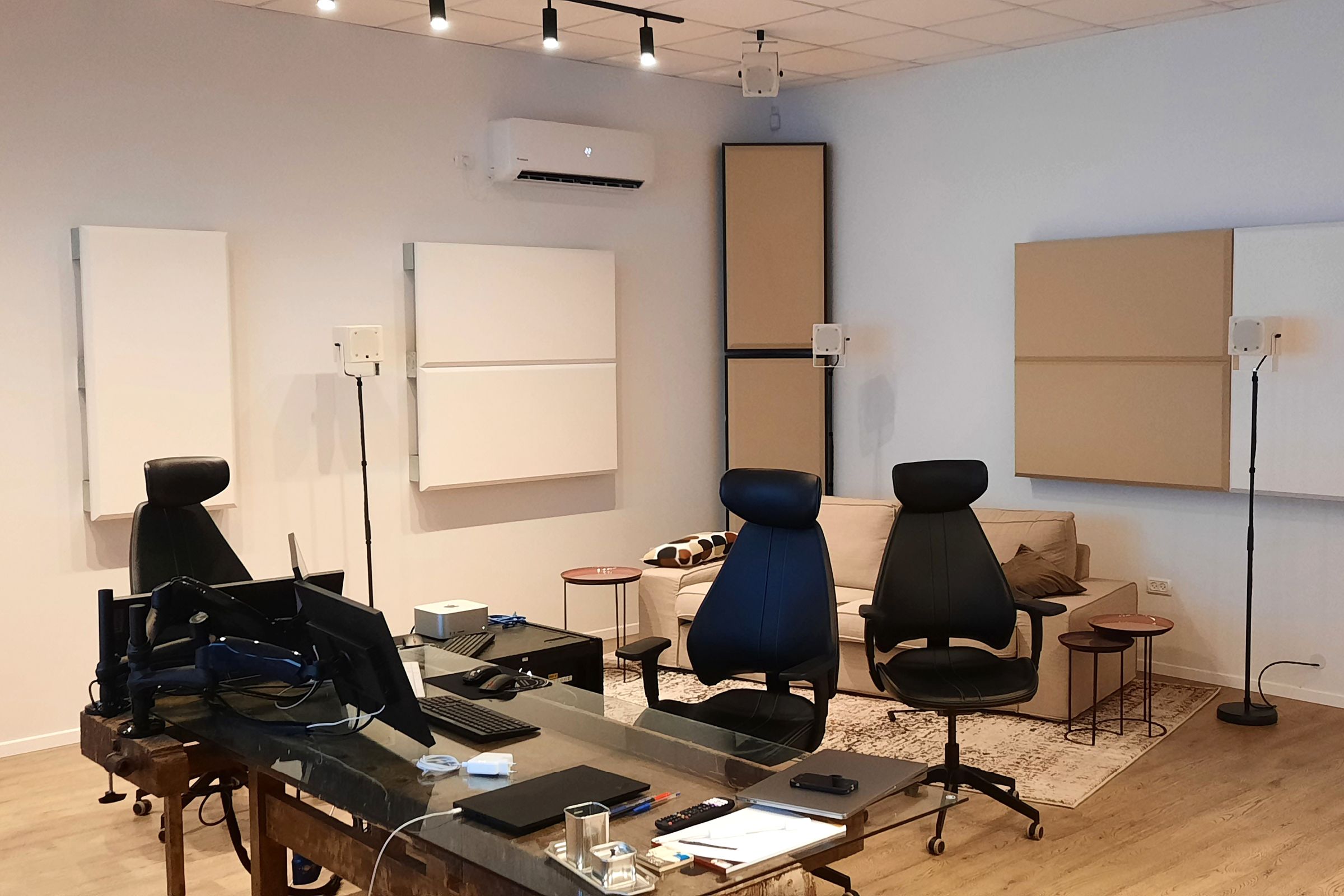Studio mixing room with beige and white acoustic wall panels, and beige corner mounted bass traps