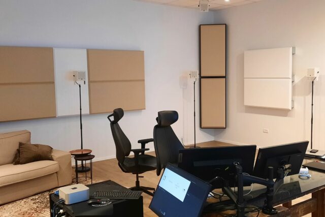 Recording studio mixing room with beige and white acoustic panels on walls, along with beige bass traps