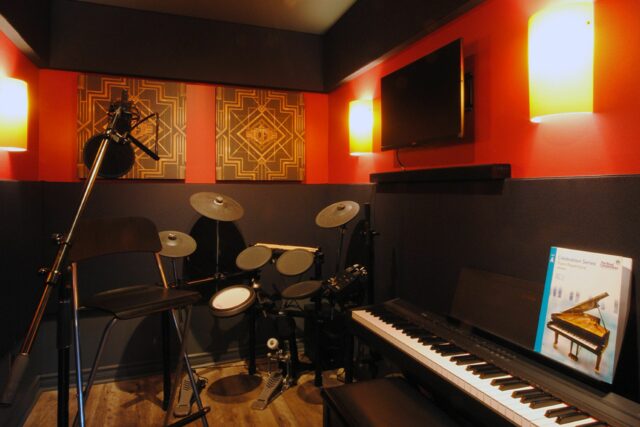 Small room with electric drum set, piano and mic set up with custom printed acoustic panels on wall