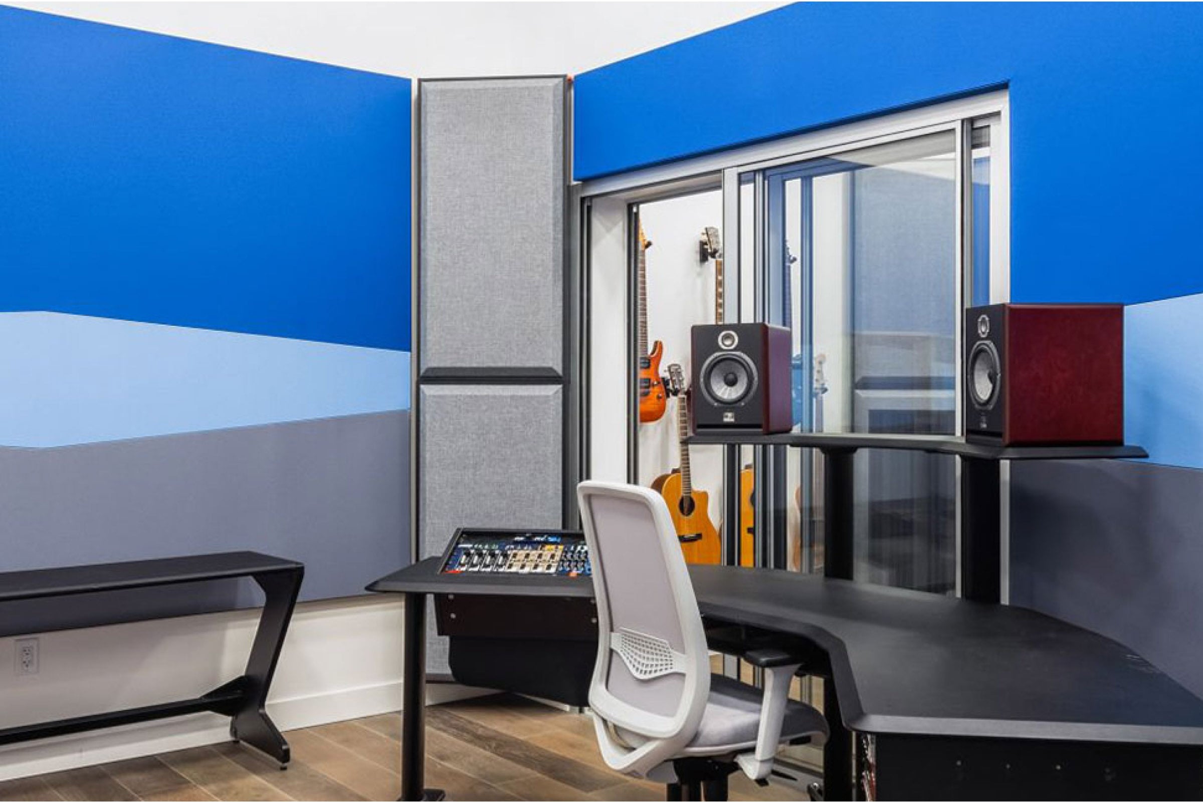 Empty recording studio with blue and grey acoustic wall and grey corner bass traps.