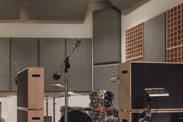 Drums set up in recording studio with sound gobos surrounding and grey acoustic panels and diffusers on walls