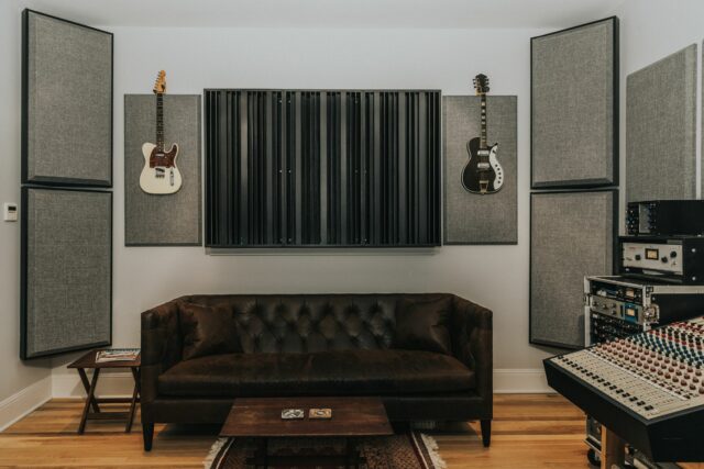 Grey acoustic wall panels and black sound diffusers hanging on walls of recording studio mixing room