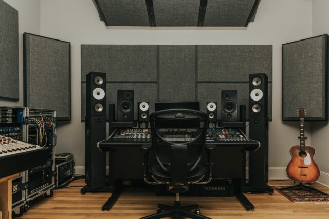Recording studio mixing station with grey acoustic panels hanging on back walls and ceiling