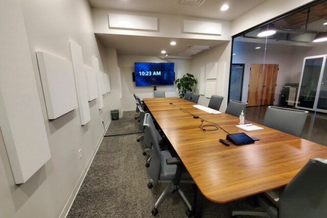 Business meeting room with large wooden table and white acoustic panels installed on walls and ceiling
