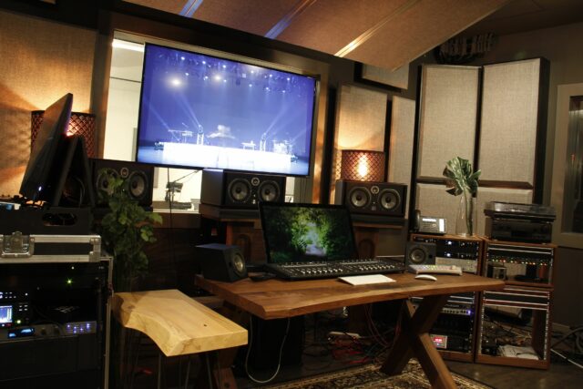 Recording studio mixing station with grey acoustic bass traps on walls and acoustic panels on ceiling
