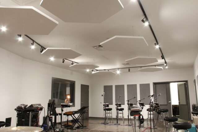 White hexagonal acoustic panels on ceiling of recording space with multiple microphones set up