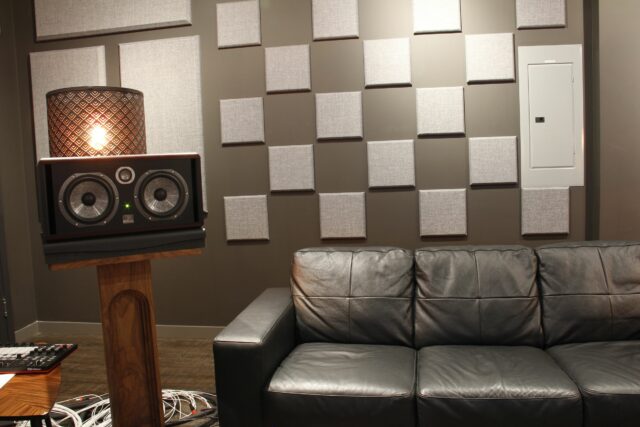 White acoustic scatter block panels on wall of recording studio with black couch below