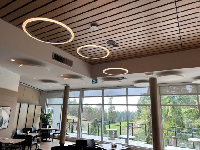 Golf clubhouse restaurant with halo lights and white circle acoustic panels on ceiling
