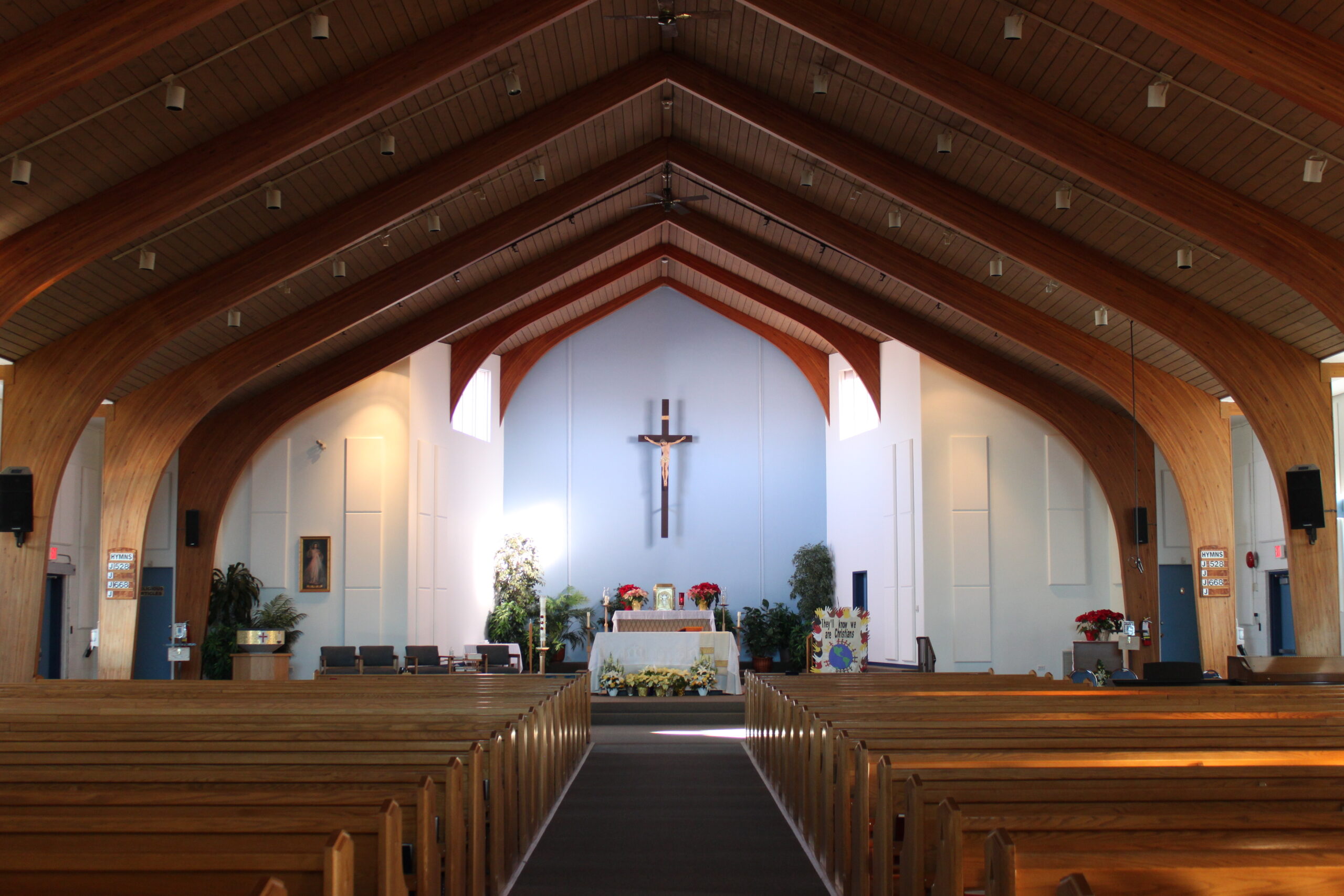 Church nave with wooden ceiliing and white acoustic panels on back wall