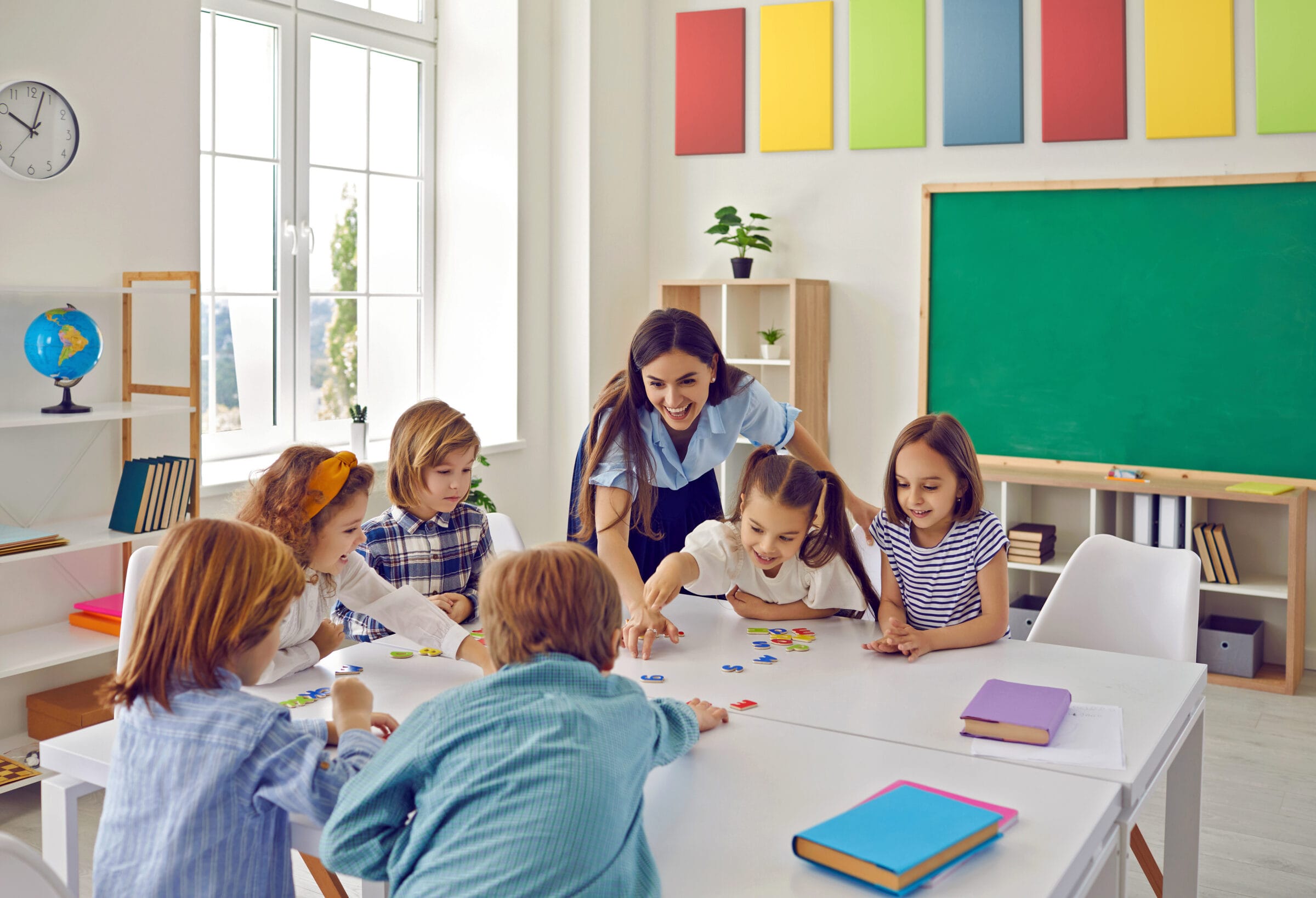 Female Teacher And Junior High School Students Have Fun Putting Together Puzzles In Class.